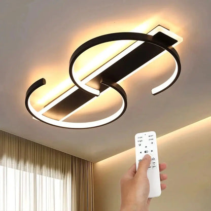 Modern S shape ceiling light fixture with a hand holding a remote control in a room setting