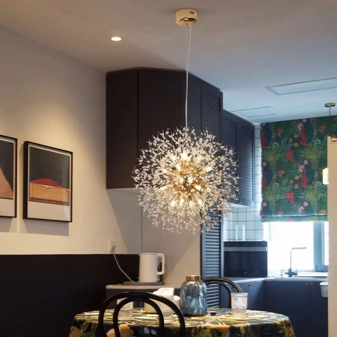 Modern chandelier hanging in a kitchen with a table and chairs underneath
